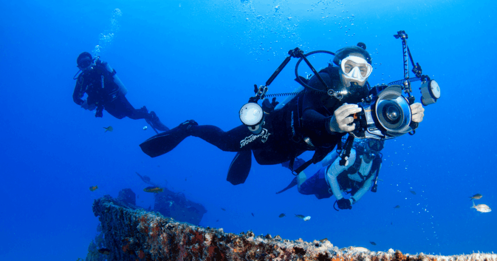 A scuba diver is holding an underwater camera