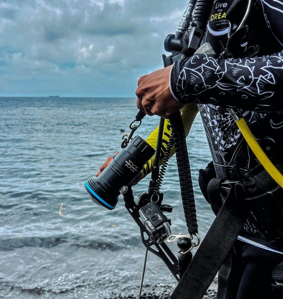 Underwater Photographer holding a GoPro in underwater casing with a light